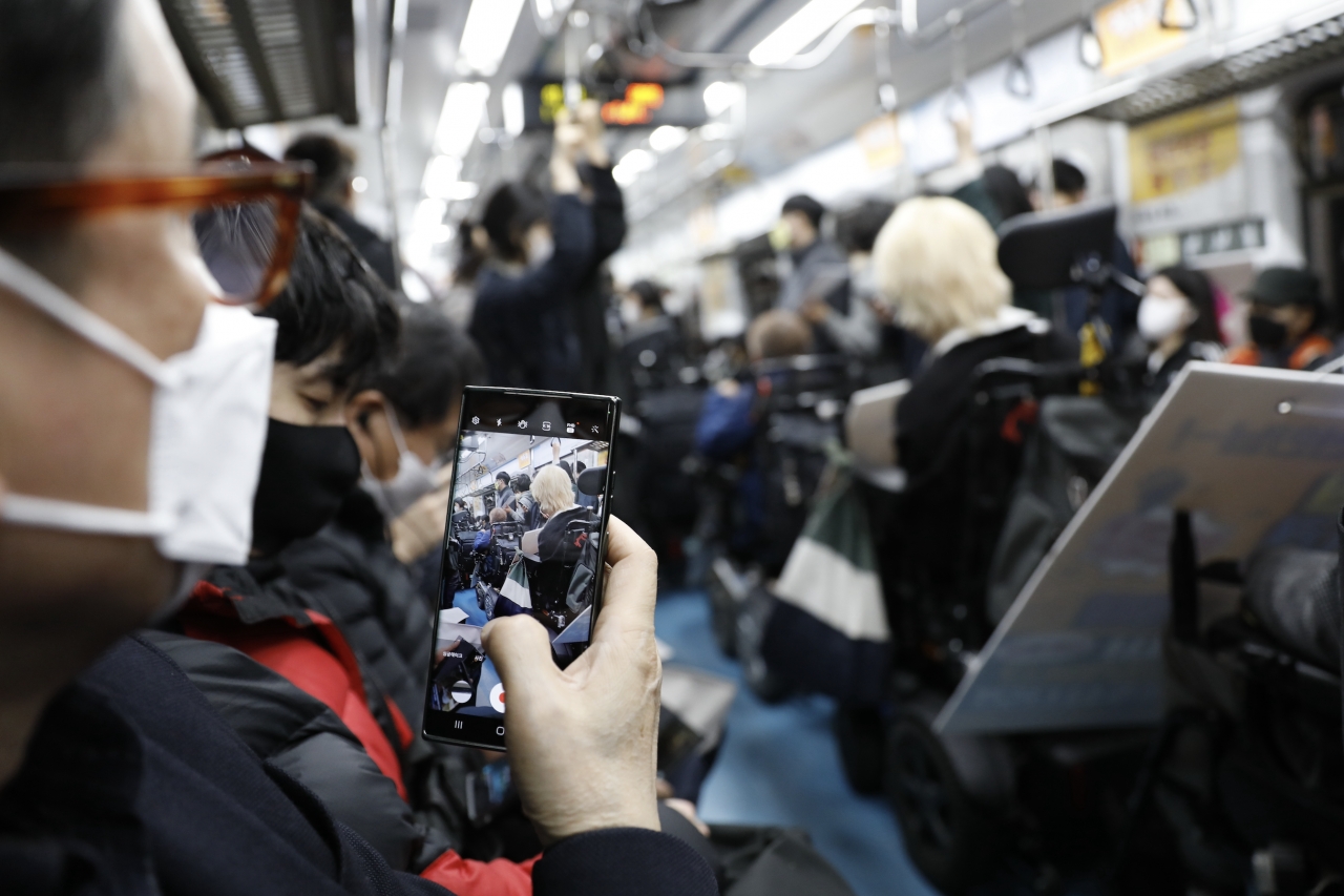 한 시민이 전철 내 일렬로 선 시위대를 촬영하고 있다. 사진 김수현 기자