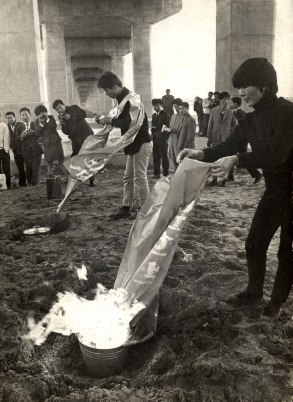 강국진, 정강자, 정찬승의 ’한강변의 타살‘(1968)은 국내 첫 집단 행위예술 작품이다. 세 명의 작가들은 양화대교 아래 구덩이에 묻혀있다가 물세례를 받고 땅 위로 다시 올라온다. 이후 ‘문화사기꾼’ 등의 문구를 적은 비닐을 태우는 화형식을 행한다. 이는 당시 한국의 구태의연한 기성 문화세력을 ‘타살’해야 함을 주장한 아방가르드 예술이었다. 사진출처 KIAF 블로그